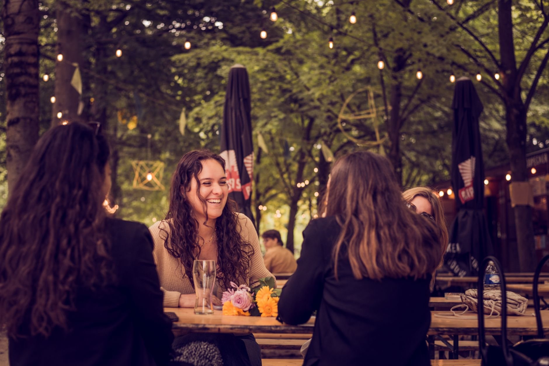 Deux amis discutant en terrasse un soir d’été, verres à la main
