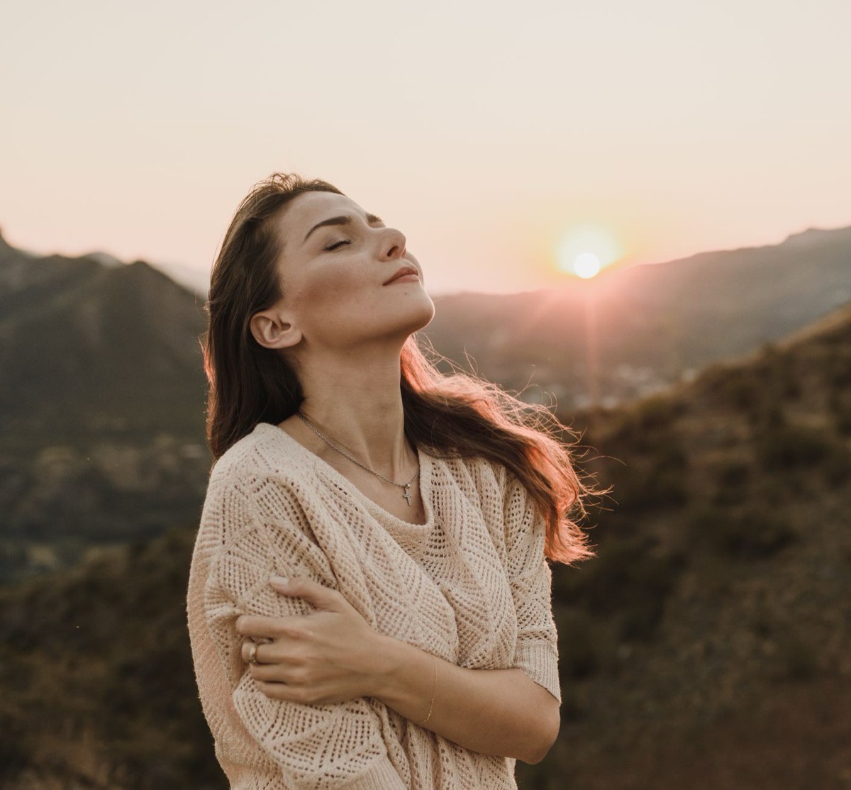 Femme les yeux fermés, visage tourné vers le soleil couchant