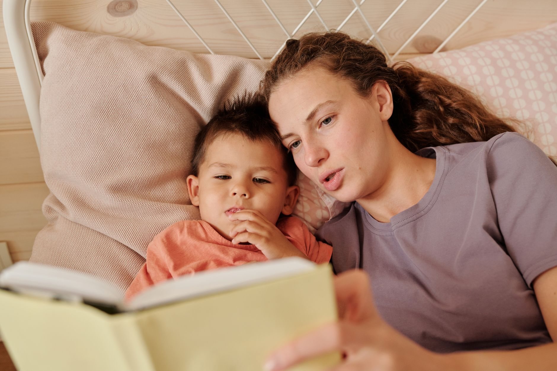 Parent et enfant lisant ensemble sur un canapé, la tête penchée vers le livre