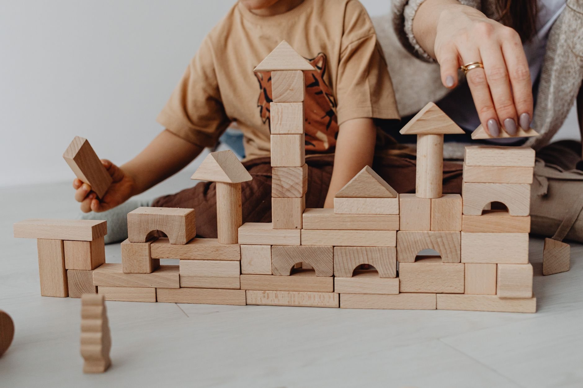 Enfant empilant des cubes de construction sous le regard d’un parent